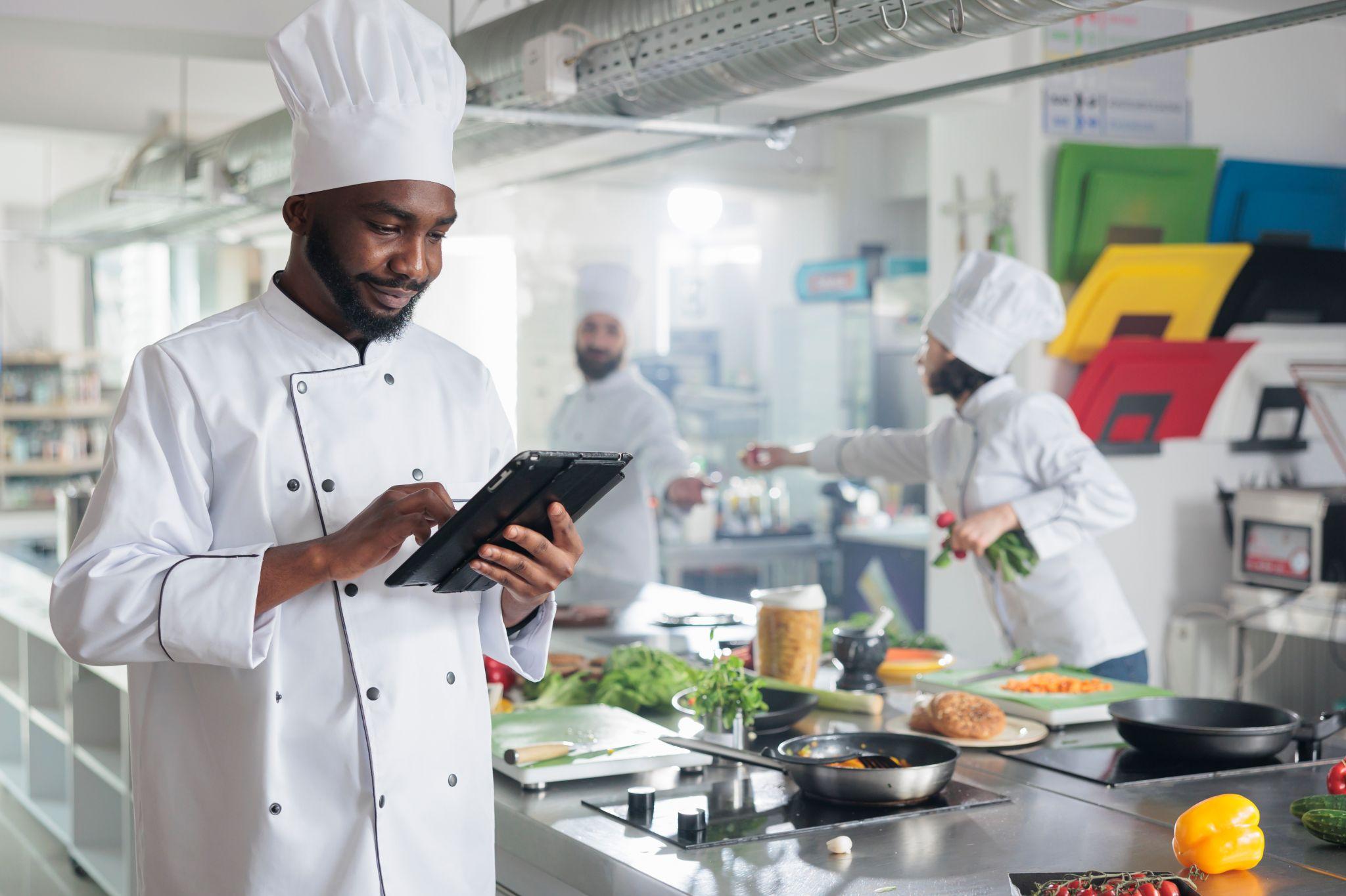 Head cook with tablet brainstorming garnish ideas for gourmet cuisine meal.